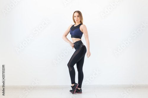 People, sport and fitness concept - attractive young woman in sportswear posing on white background