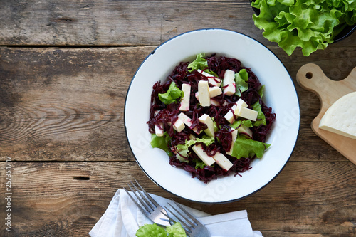 Beet salad with cheese and lettuce in a white bowl