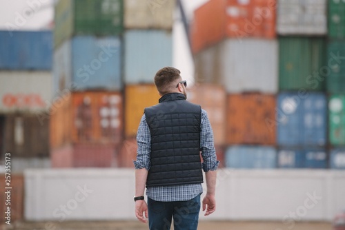 A man with a beard and sunglasses in a plaid shirt and waistcoat posing on the street to advertise men's clothing. Advertising menswear