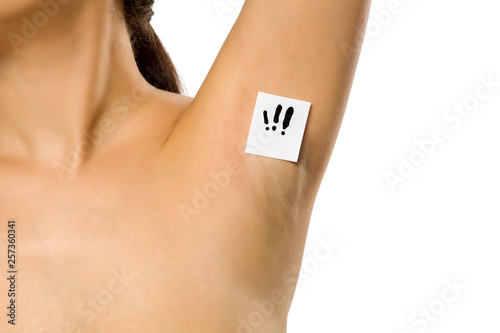 Woman shows her underarm with the exclamation mark on her on white background