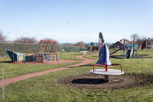 Peterlee, Durham / Great Britain - March 17, 2019: Empty childs playground in enclosed park area in residential area.  Various climbing frames and structures visible