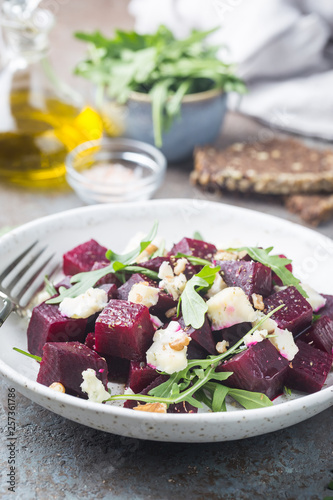 beetroot salad with blue cheese, arugula and walnut in a white plate on gray background