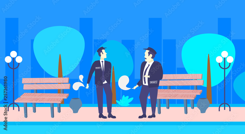 Naklejka premium two security guards smoking cigarette unhealthy lifestyle concept men colleagues in uniform standing together night urban park cityscape background full length horizontal