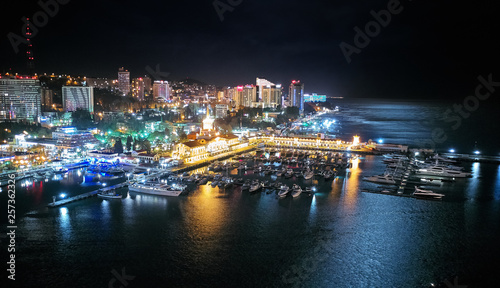 Sochi sea port. Aerial drone. Berth for marine yachts and boats. The historic building of the seaport. Evening illumination of the city.