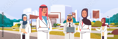 group of arabic doctors team in uniform standing together in front of hospital building medical clinic exterior cityscape background portrait flat horizontal