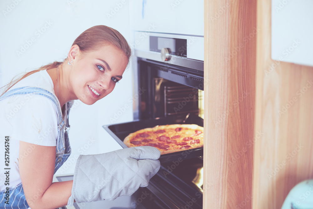 Happy young woman cooking pizza at home