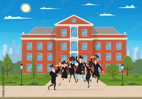 happy graduates jump and rejoice in the courtyard in front of the university.