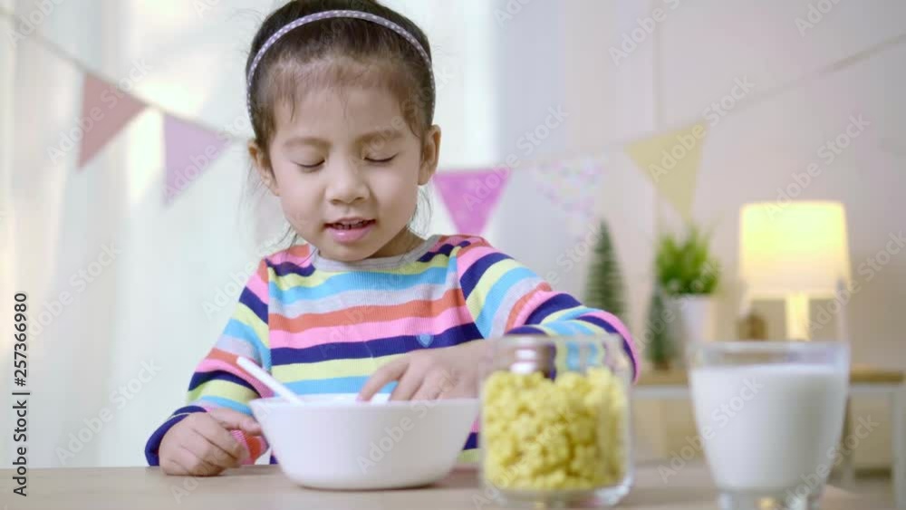 Little asian child girl is eating cereal with milk on the morning, Healthy food habits concept Little asian child girl is eating cereal with milk on the morning, Healthy food habits concept