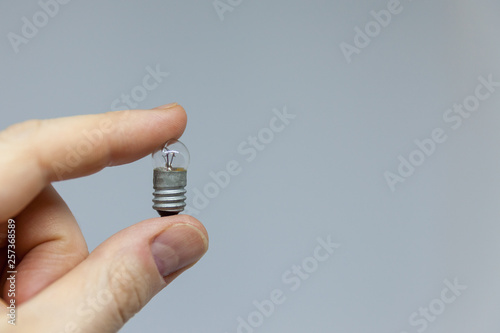 little light bulb in hand on gray background