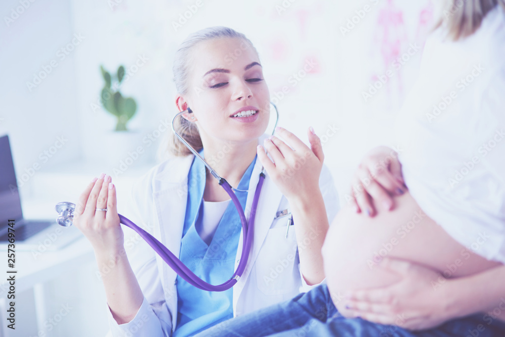 Young woman doctor with stethoscope speaking with pregnant woman at hospital. Young woman doctor with stethoscope speaking with pregnant woman at hospital.