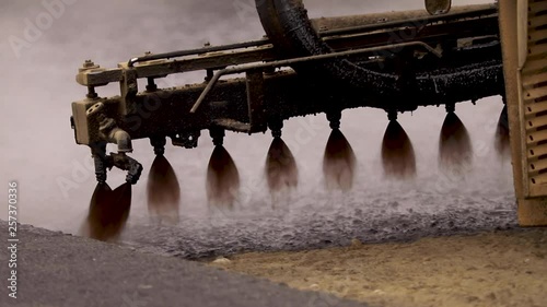 Machine sprays bitumen on the new road. Asphalt
