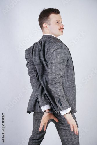 expensively dressed thief suffers from kleptomania and is arrested for a crime. a man in a business fashionable suit stands on a white background in the Studio.