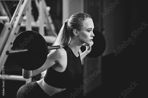 Fit woman working out with barbell on shoulders. © serhiibobyk