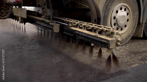 Machine sprays bitumen on the new road. Asphalt