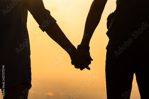 Silhouette hands of young couple at sunset.