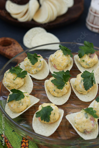 Appetizer on chips with salmon, eggs and cheese