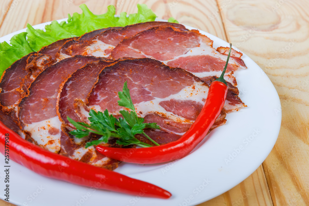 Sliced dried pork neck with greens and chili on dish Sliced dried pork neck with greens and chili on dish
