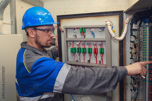 Photos electromechanic in electrical safety gloves holds power cable, cabling connectio