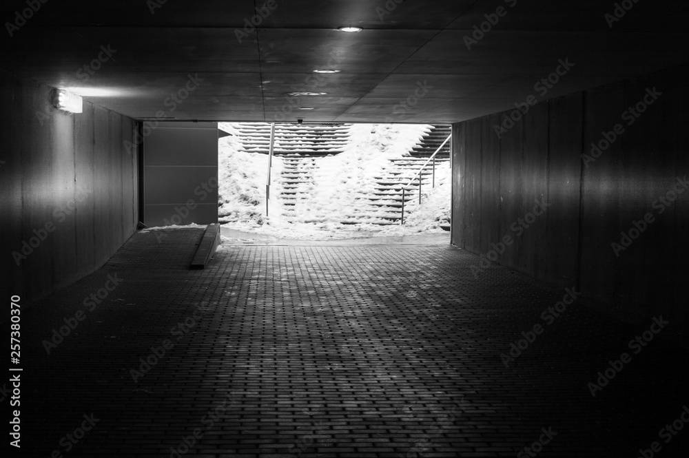 An underground passage in winter with some snow on the stairs in black and white