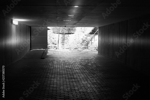 An underground passage in winter with some snow on the stairs in black and white