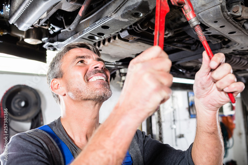 Smiling mature man repairing the car