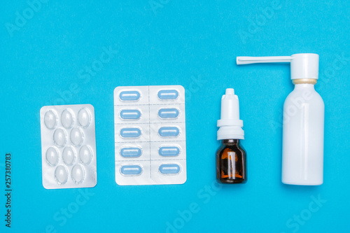 Treatment of colds and flu. Various medicines, sprays from a stuffy nose and a pain in a throat on a blue background. Copy space. Medicine flat lay