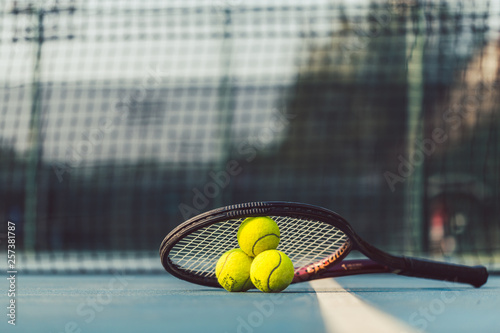 Three tennis balls on a professional racket on acrylic blue surface photo