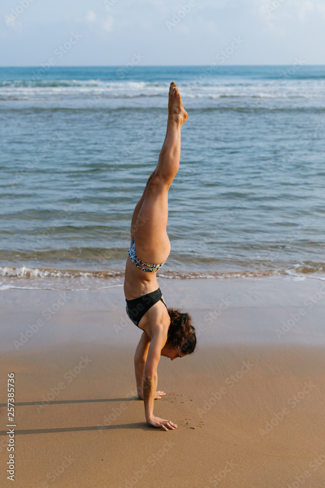 Ταπετσαρία Fit young woman in bikini doing headstand gymnastic balance exersice at the beach