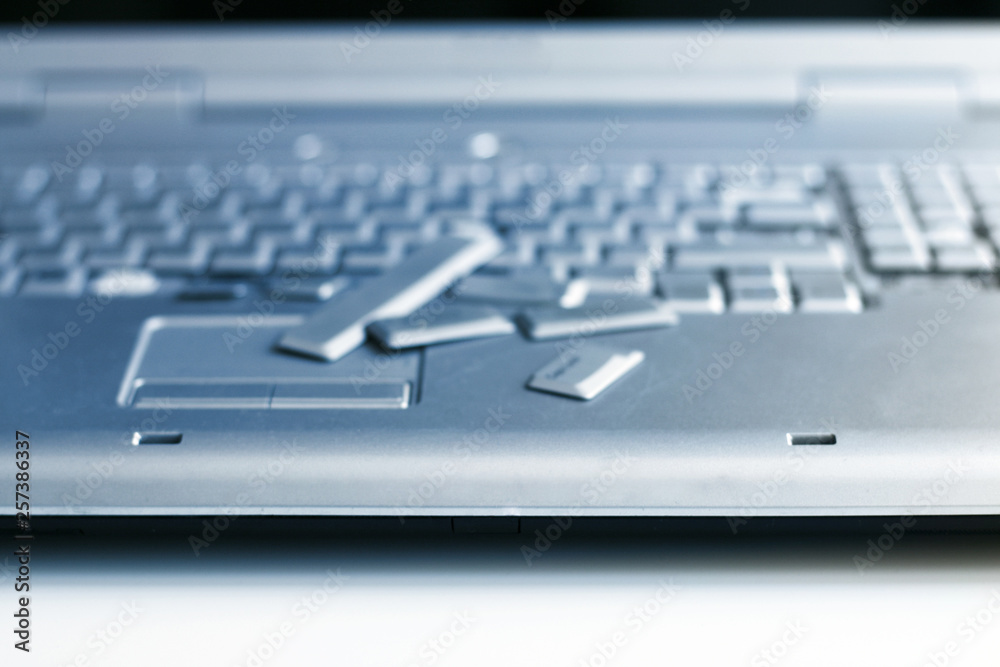 Silver laptop with broken keyboard. A close-up picture of part of broken laptop. Silver laptop with broken keyboard. A close-up picture of part of broken laptop.