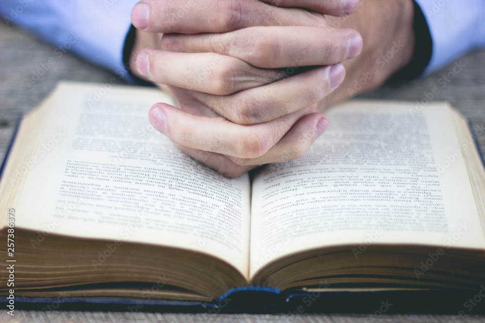 Fototapeta premium praying hands over a holy bible