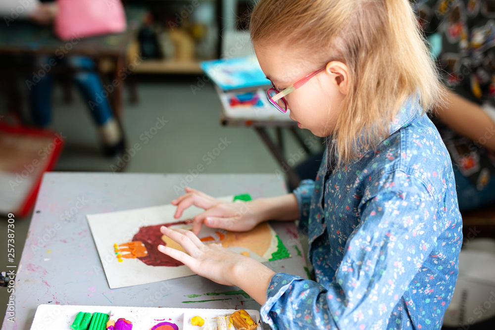 Portrait of adorable little girl smiling happily while enjoying art and craft lesson in art school working together with other kids Portrait of adorable little girl smiling happily while enjoying art and craft lesson in art school working together with other kids