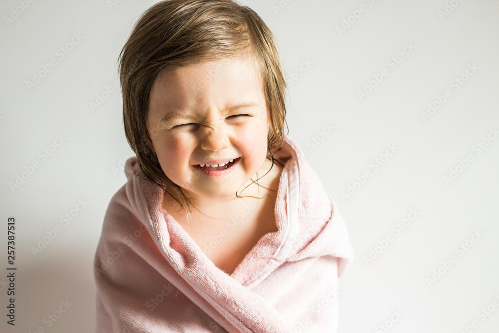 Funny Emotional Toddler Baby Girl Wrapped in a Towel After Shower or Bath on Neutral Background Funny Emotional Toddler Baby Girl Wrapped in a Towel After Shower or Bath on Neutral Background