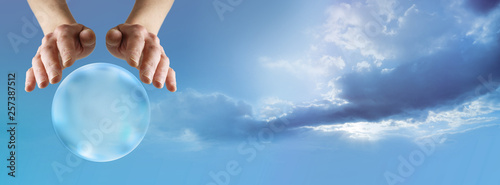 Find out what your future holds with a Crystal Ball Reading - female hands hovering above a large scrying ball against a beautiful blue sky and cloud  background with copy space photo