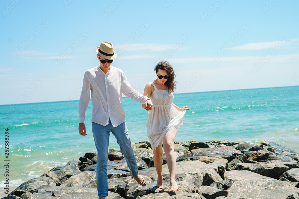 A young couple of lovers, a guy and a girl on the ocean, in white clothes on the stones. A young couple of lovers, a guy and a girl on the ocean, in white clothes on the stones.
