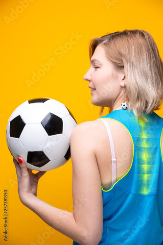 Photo from back of blonde with soccer ball on yellow background