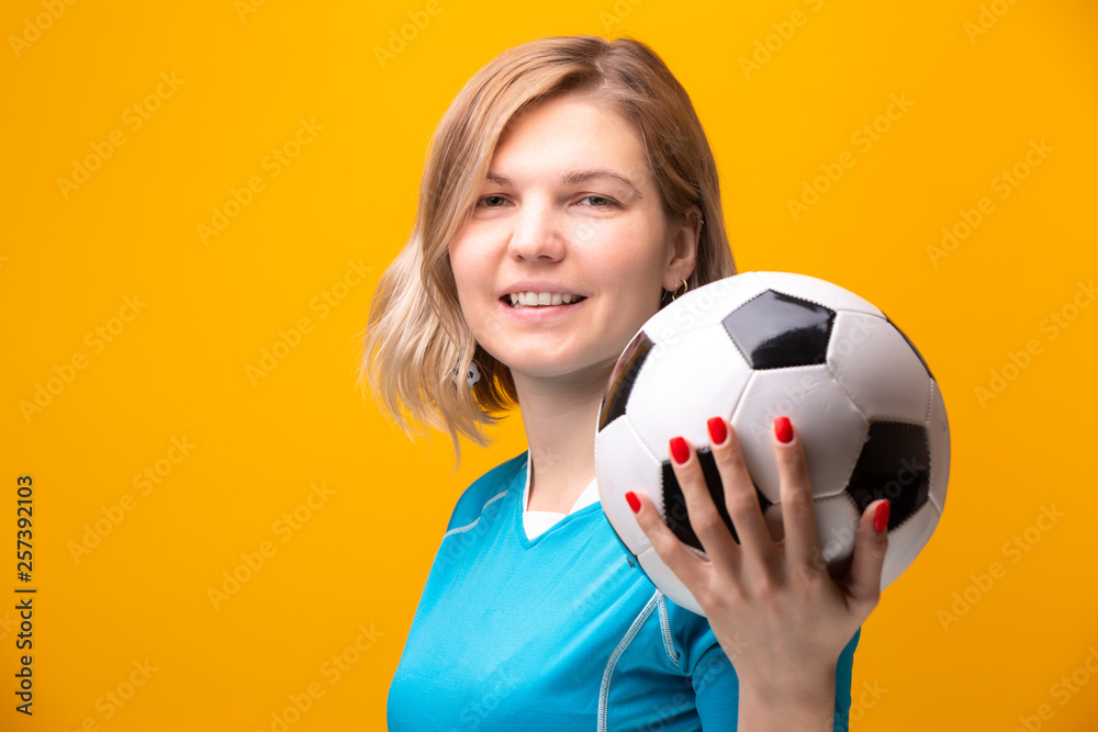 Photo of blonde with soccer ball on yellow background Photo of blonde with soccer ball on yellow background