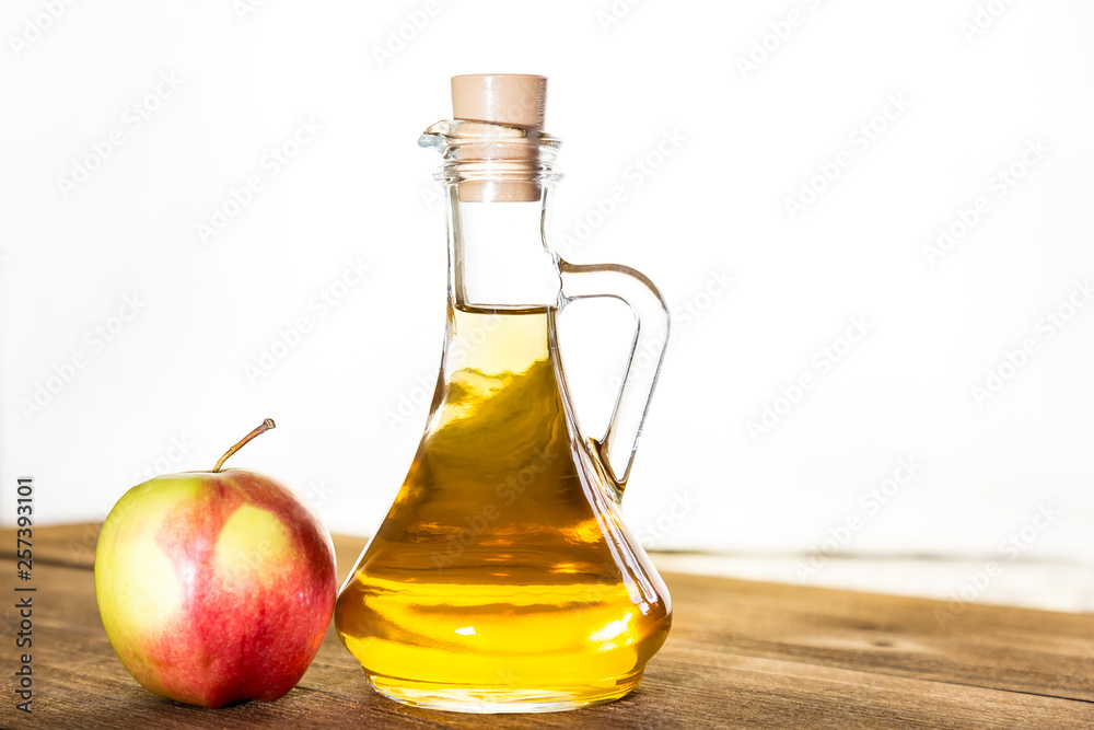 Processing of an agricultural crop of red and green apples. Home canning, healthy diet vegetarian food. Apple cider vinegar, juice, cider in a glass jar next to ripe fruit Processing of an agricultural crop of red and green apples. Home canning, healthy diet vegetarian food. Apple cider vinegar, juice, cider in a glass jar next to ripe fruit