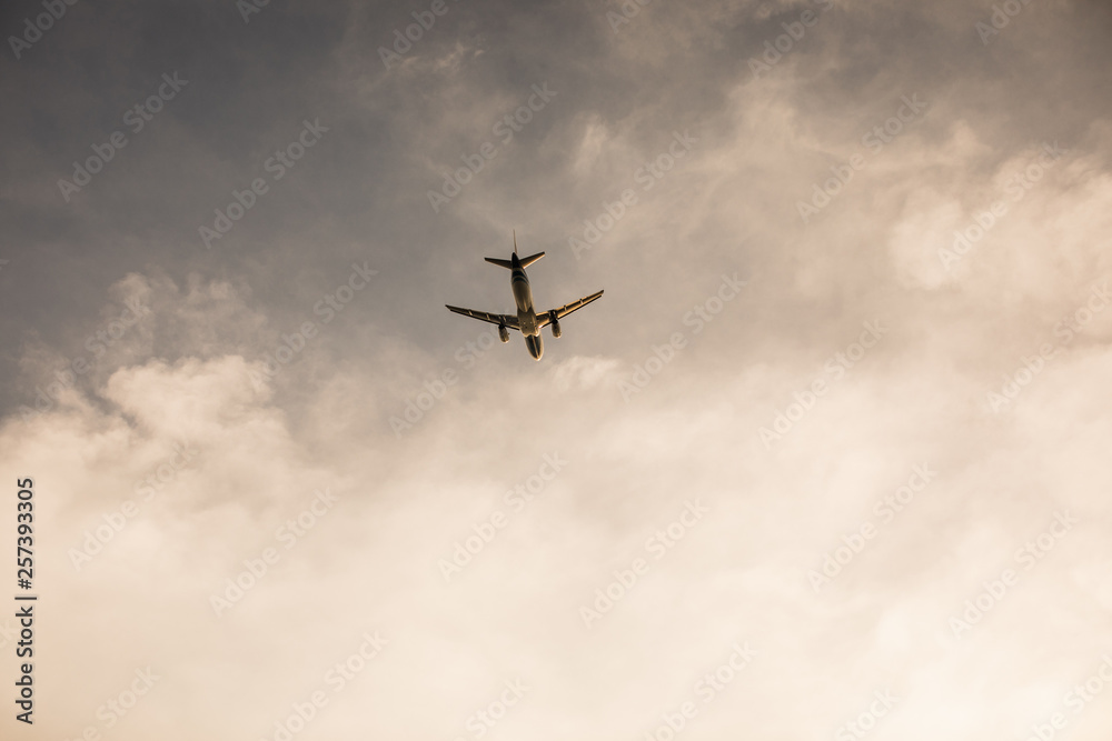 Airplane flying above tropical sea at sunset