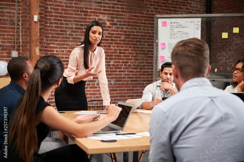 Canvas Print Young Businesswoman Standing And Leading Office Meeting Around Table