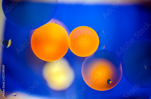 orange and yellow oil stains on water on blue background