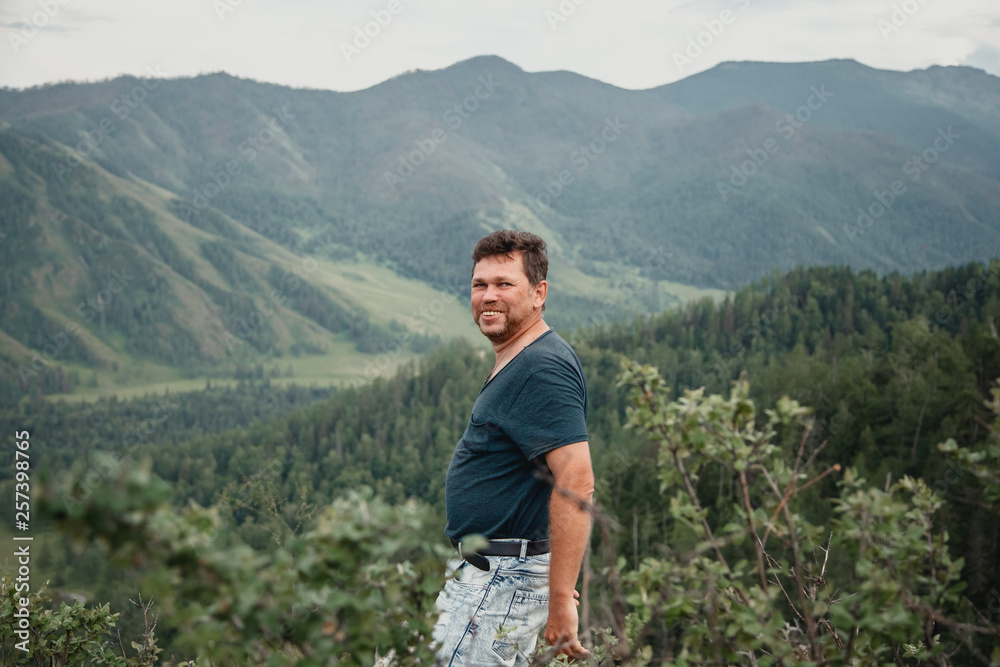 Portrait of a happy man on a mountain view background. The journey to the mountains