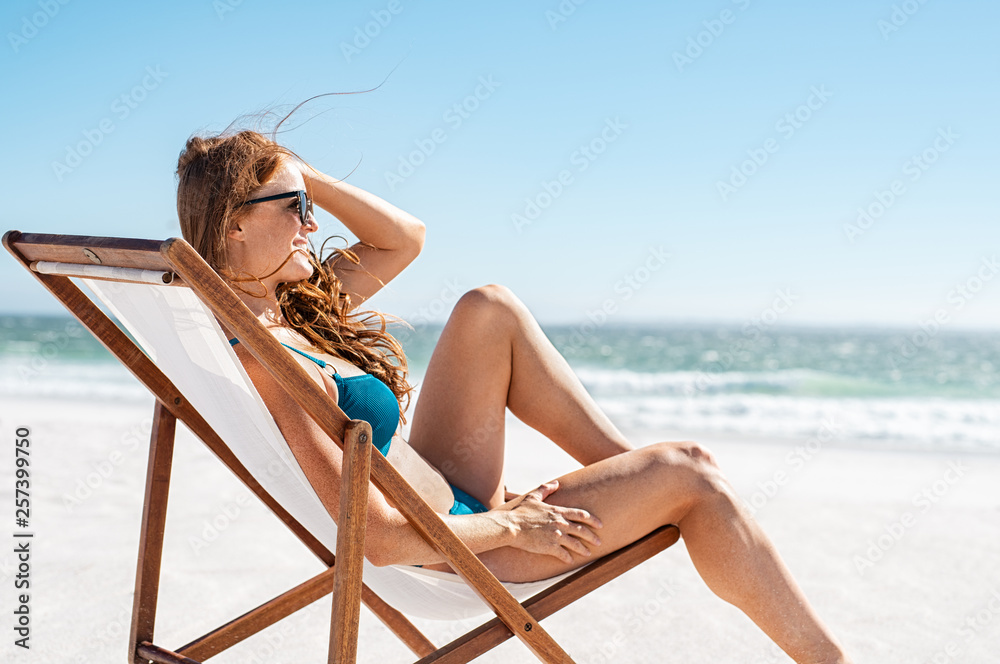 Relaxed woman sunbathing at beach - obrazy, fototapety, plakaty 