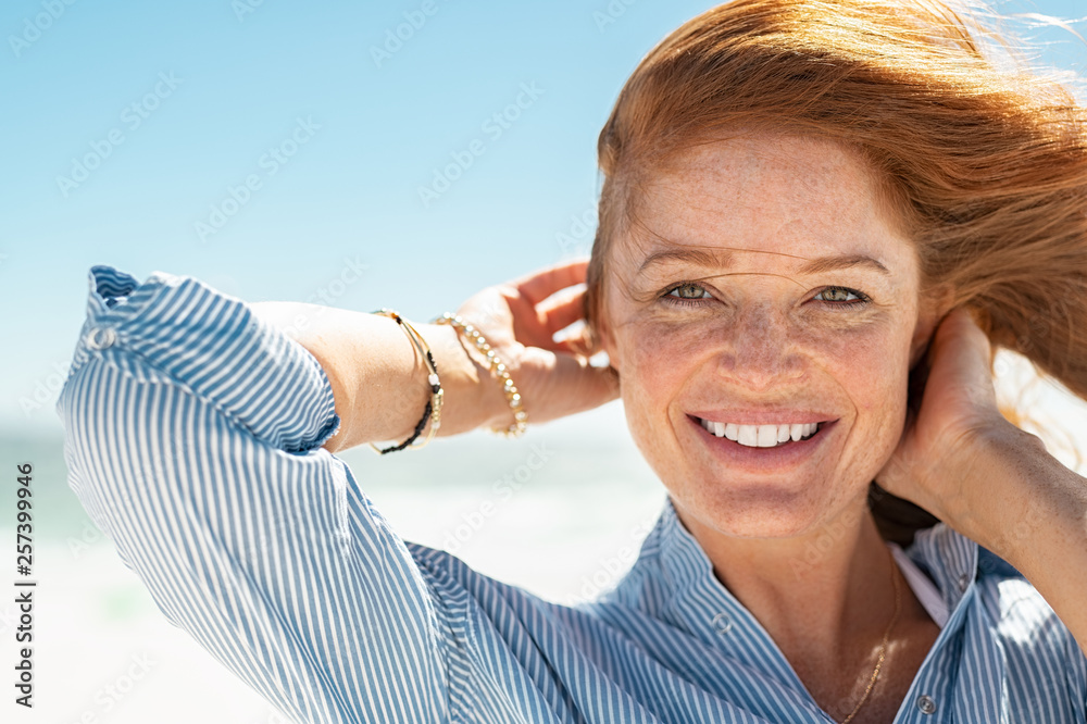 Smiling mature woman at beach - obrazy, fototapety, plakaty 