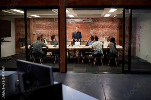 Business Team Having Late Night Meeting Sitting Around Boardroom Table