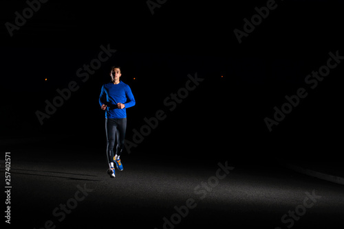 Young Man in Blue Running at Night. Urban Running. Healthy Lifestyle and Sport Concept. © Maksym Protsenko