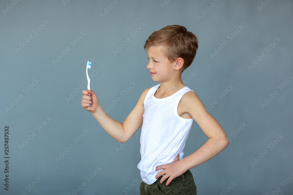 Boy with a toothbrush on a gray background. Concept of Children and Hygiene Boy with a toothbrush on a gray background. Concept of Children and Hygiene