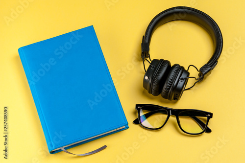 Black stylish headphones, smartphone, glasses and notebook