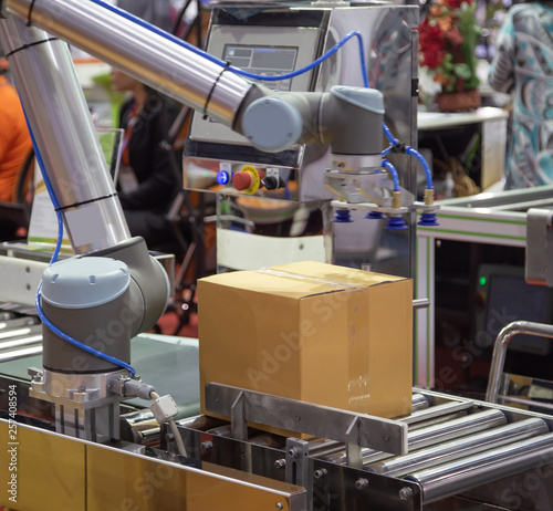 The universal robot lifting cardboard to conveyor in industry production line photo