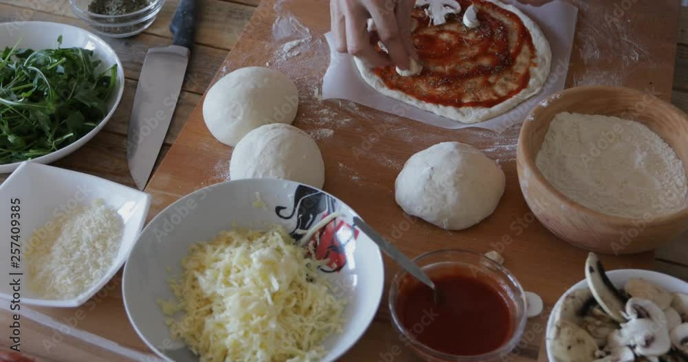 Home made pizza, making process, mushrooms sprinkled at dough Home made pizza, making process, mushrooms sprinkled at dough