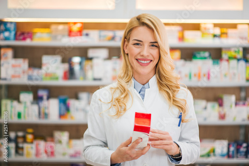 Smiling pharmacist holding medication, looking at camera. photo